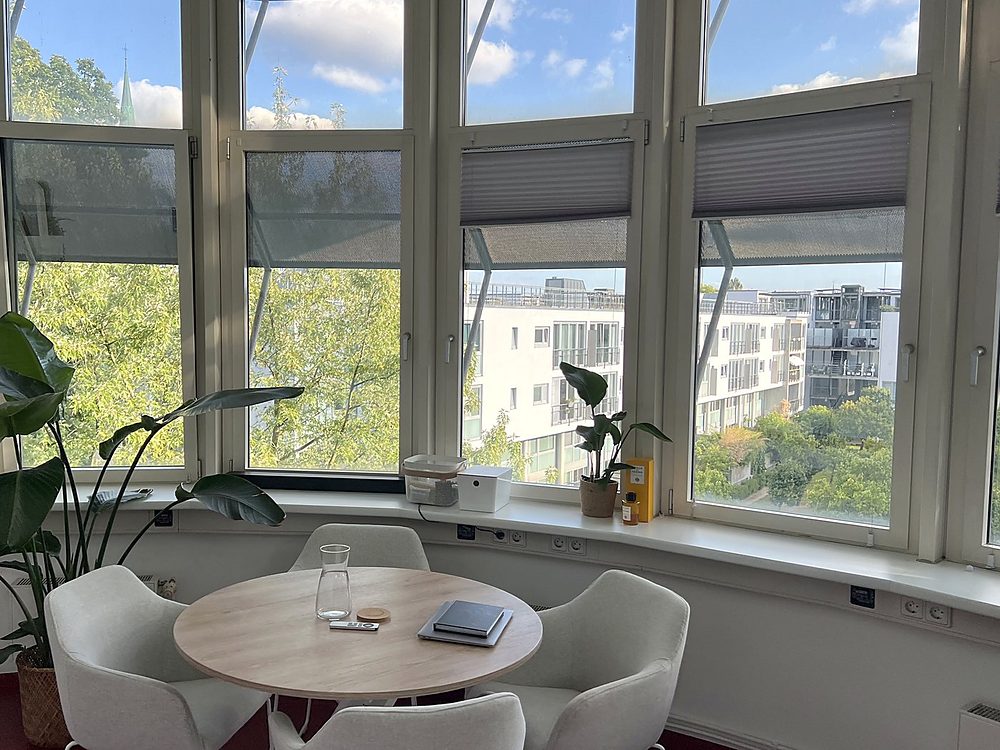 Runder Besprechungstisch mit vier Sesseln vor der Fensterfront in unserem Büro